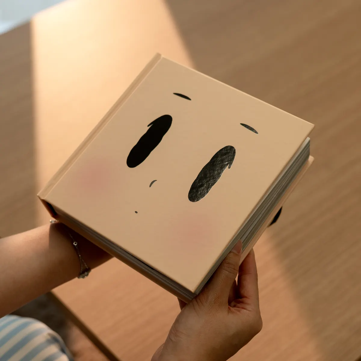 The closed book held in two hands, showing its square shape and the thickness of 576 pages