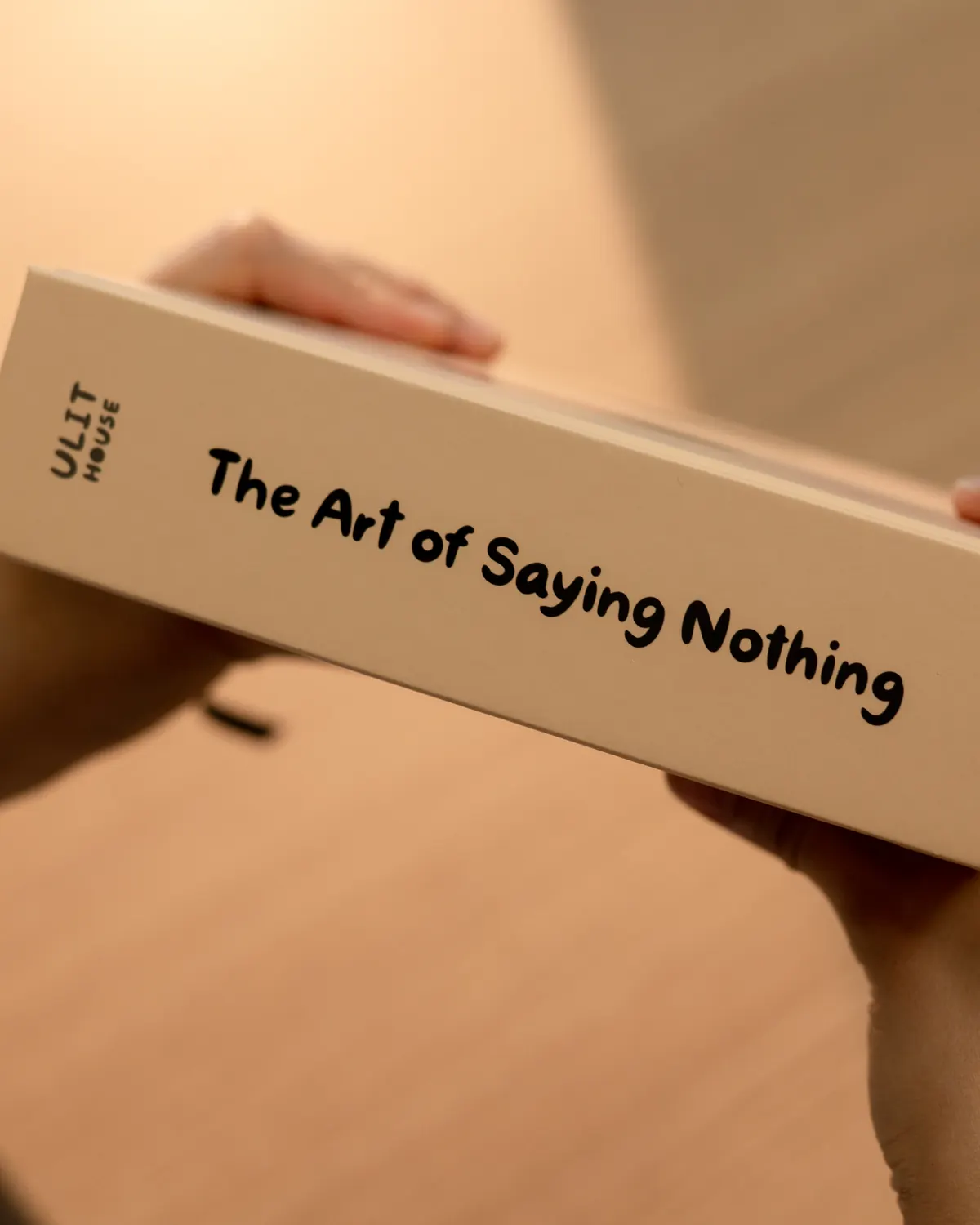 The spine of the book held in two hands, showing the title and the Ulithouse mark